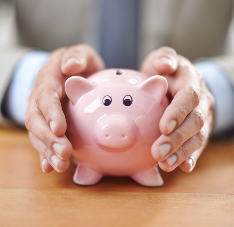 Protecting his assets. Cropped image of a businessmans hands covering a piggybank