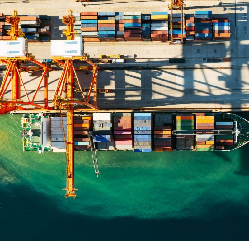 Aerial view of containers loading and unloading to the ship in the sea port. Logistic and transportation of goods. Crisis and shortage of containers in the world.