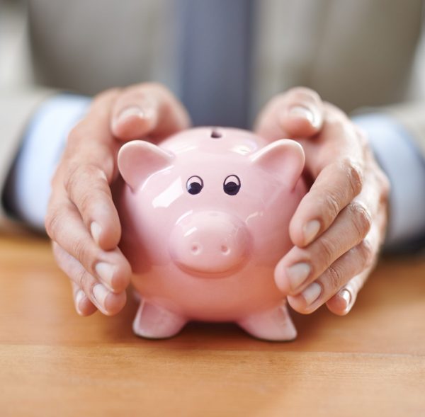 Protecting his assets. Cropped image of a businessmans hands covering a piggybank