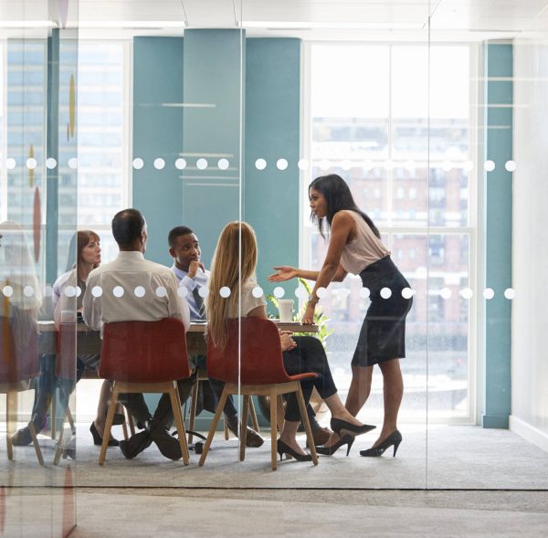 Female boss stands leaning on table at business meeting